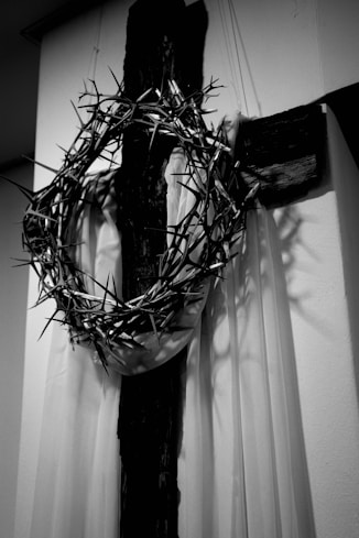 A black and white photo of a crucifix with a wreath on it