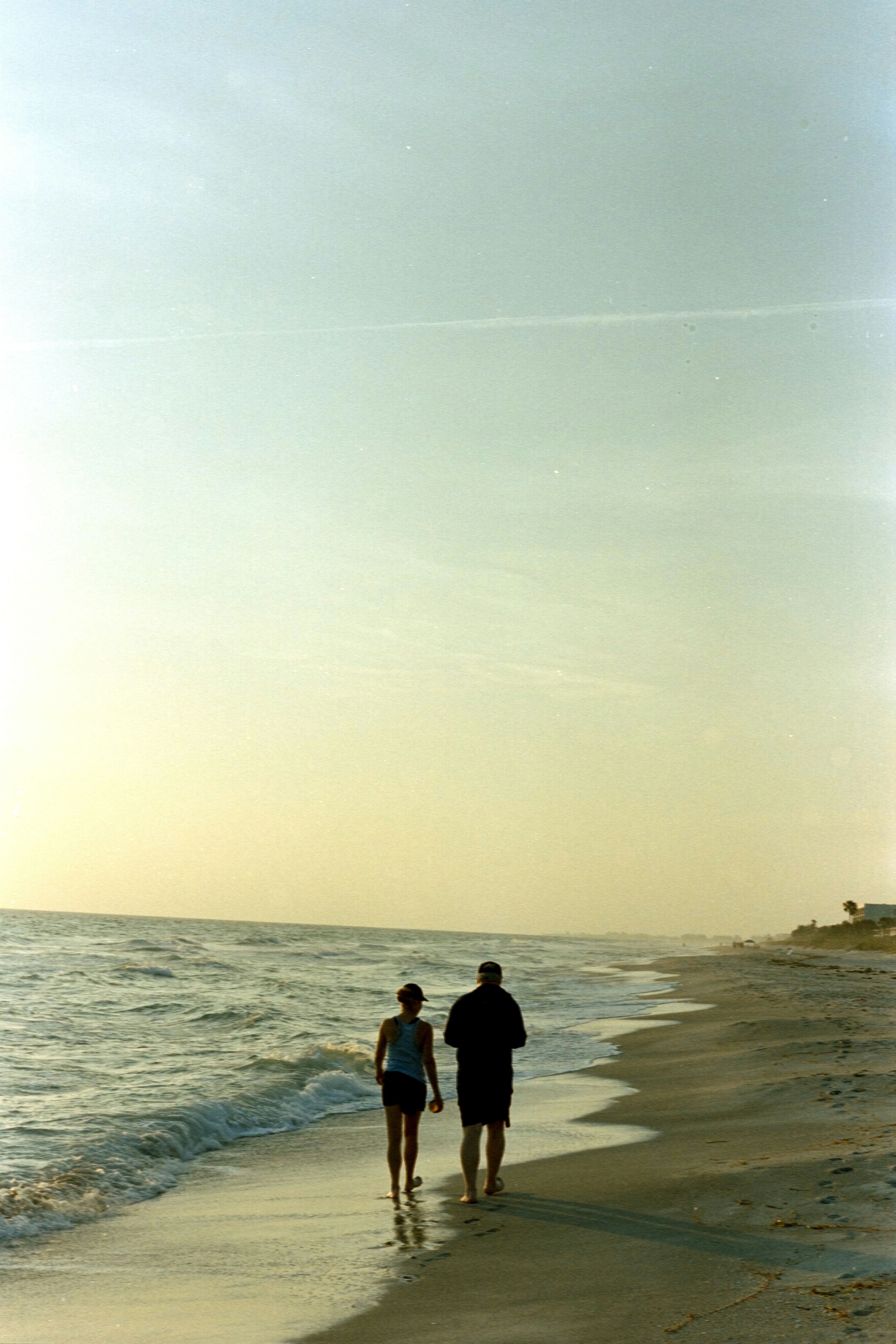 A man and a woman are walking on the beach