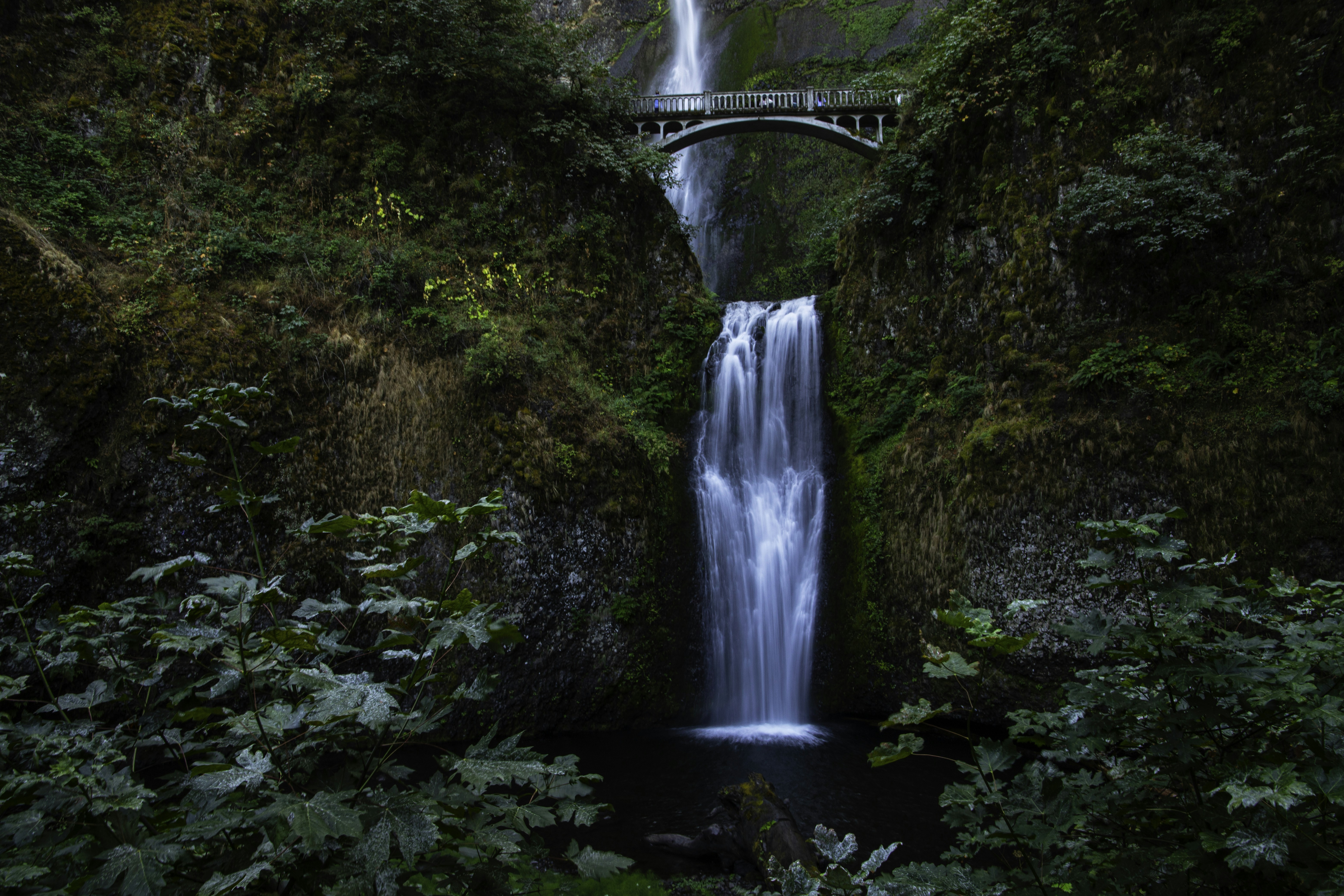 A waterfall with a bridge in the middle of it