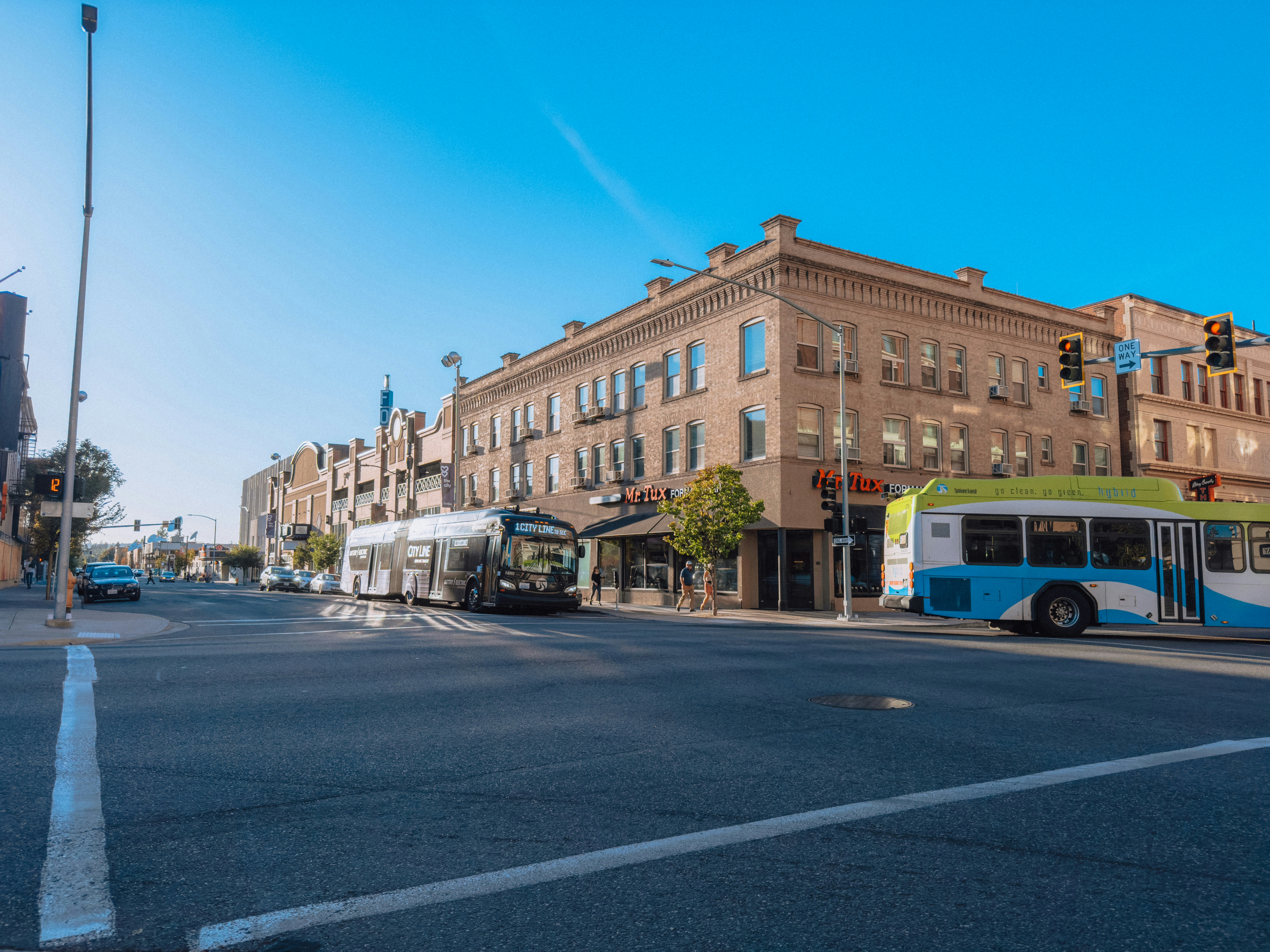 A blue and white bus driving down a street next to tall buildings