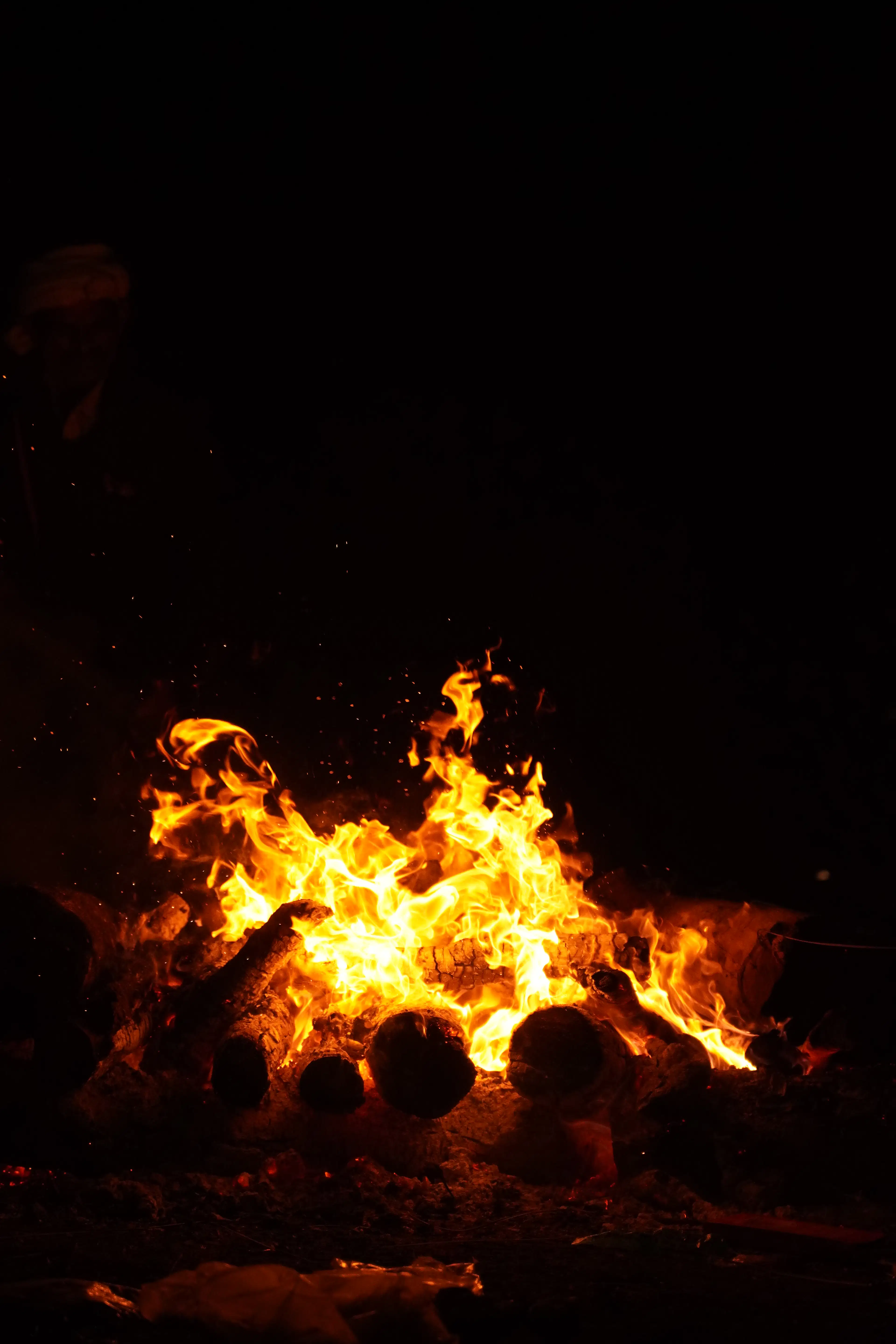 Tall flames of an evening bonfire crackling on logs