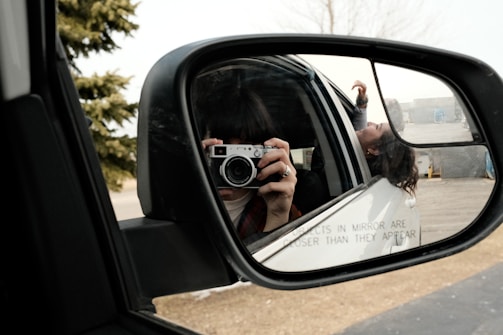 A person taking a picture of themselves in a car mirror