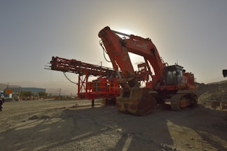 A large red machine sitting on top of a dirt field