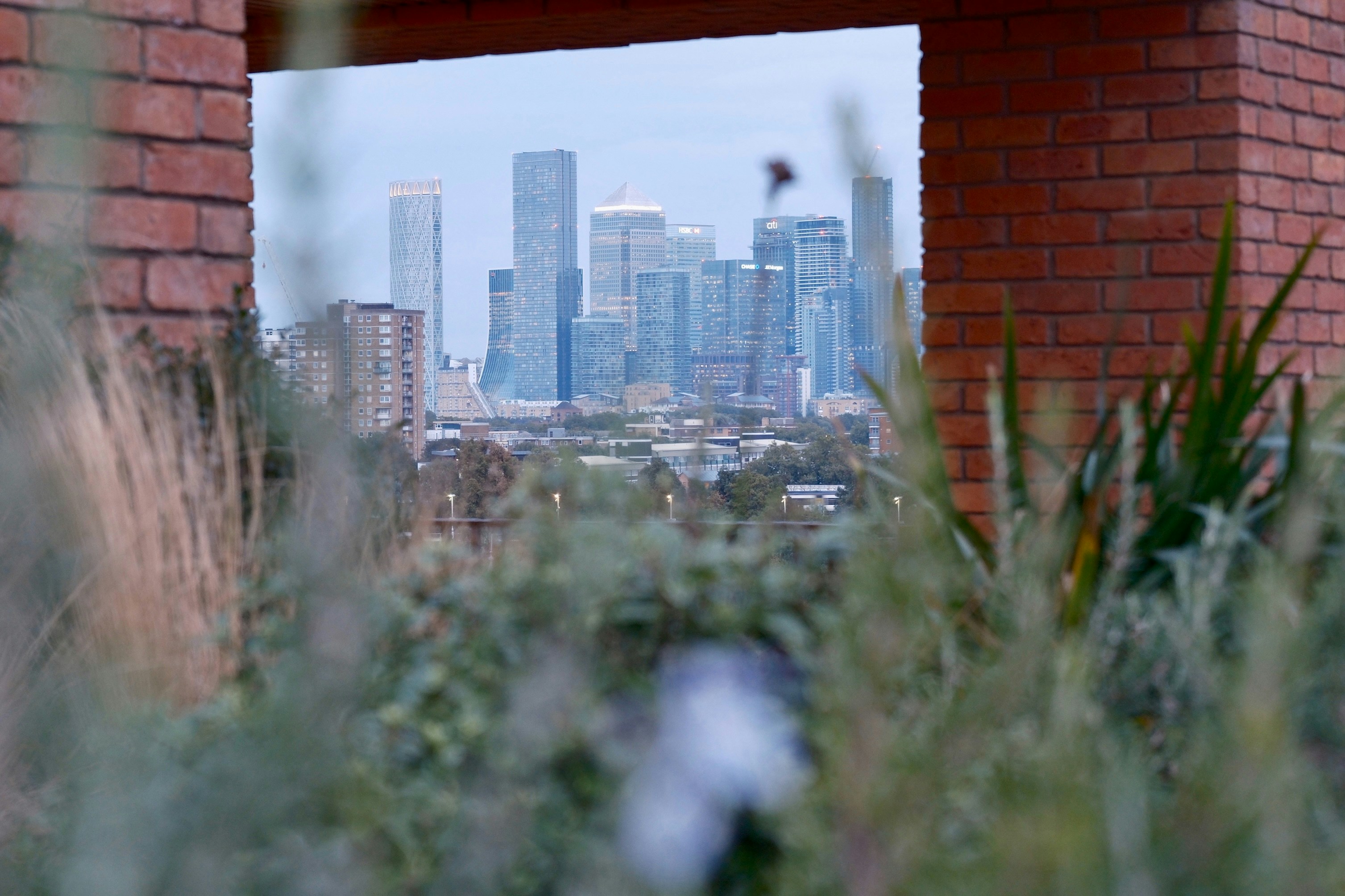 A view of a city through a hole in a brick wall