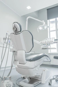 A white dental chair in a room with a window