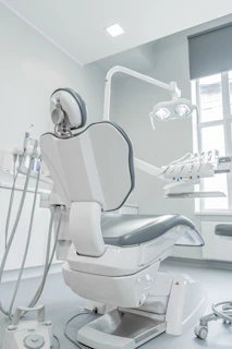 A white dental chair in a room with a window