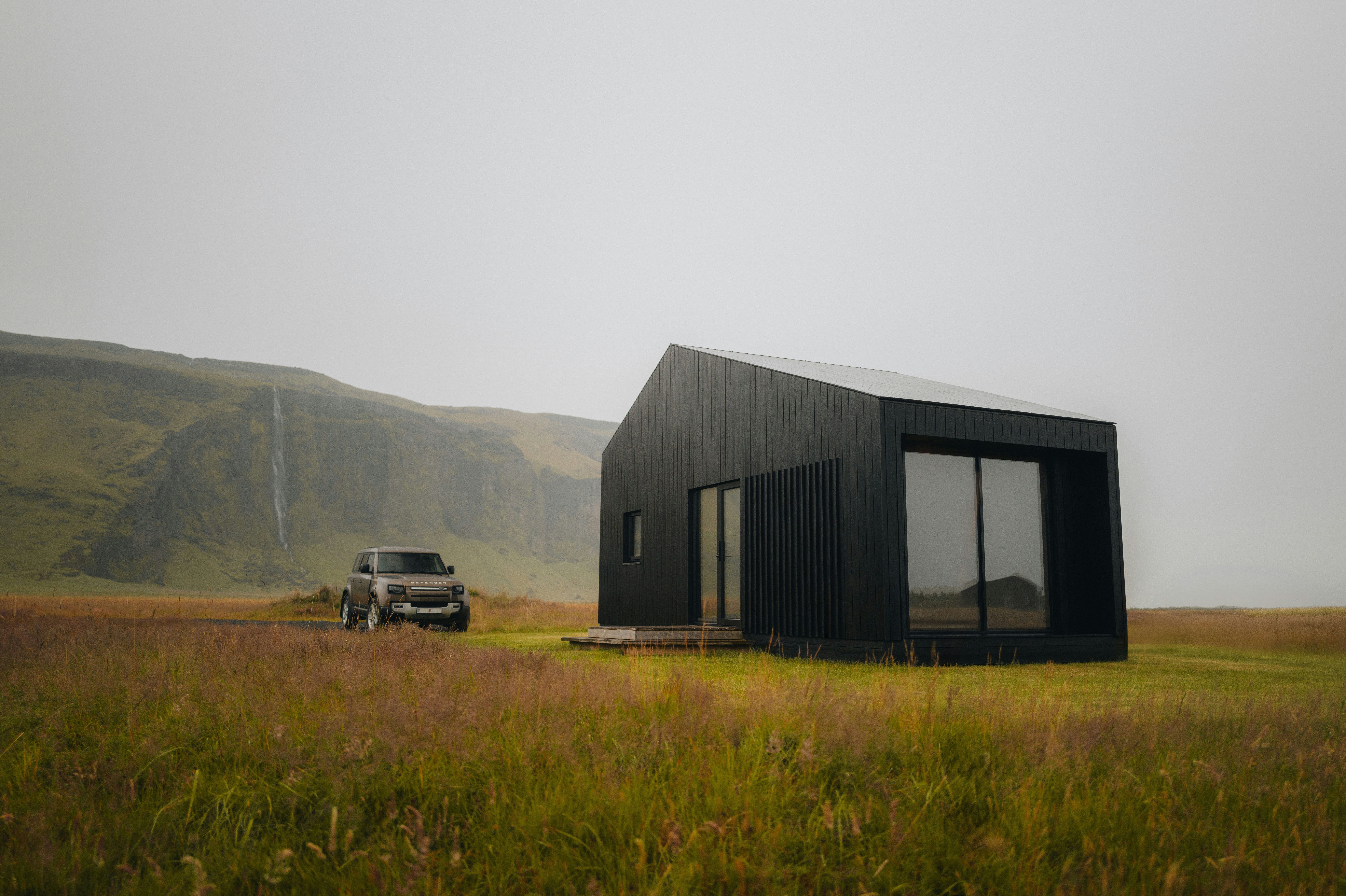 A truck parked in a field next to a black building