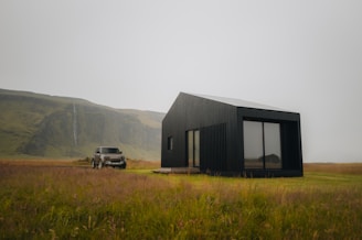 A truck parked in a field next to a black building
