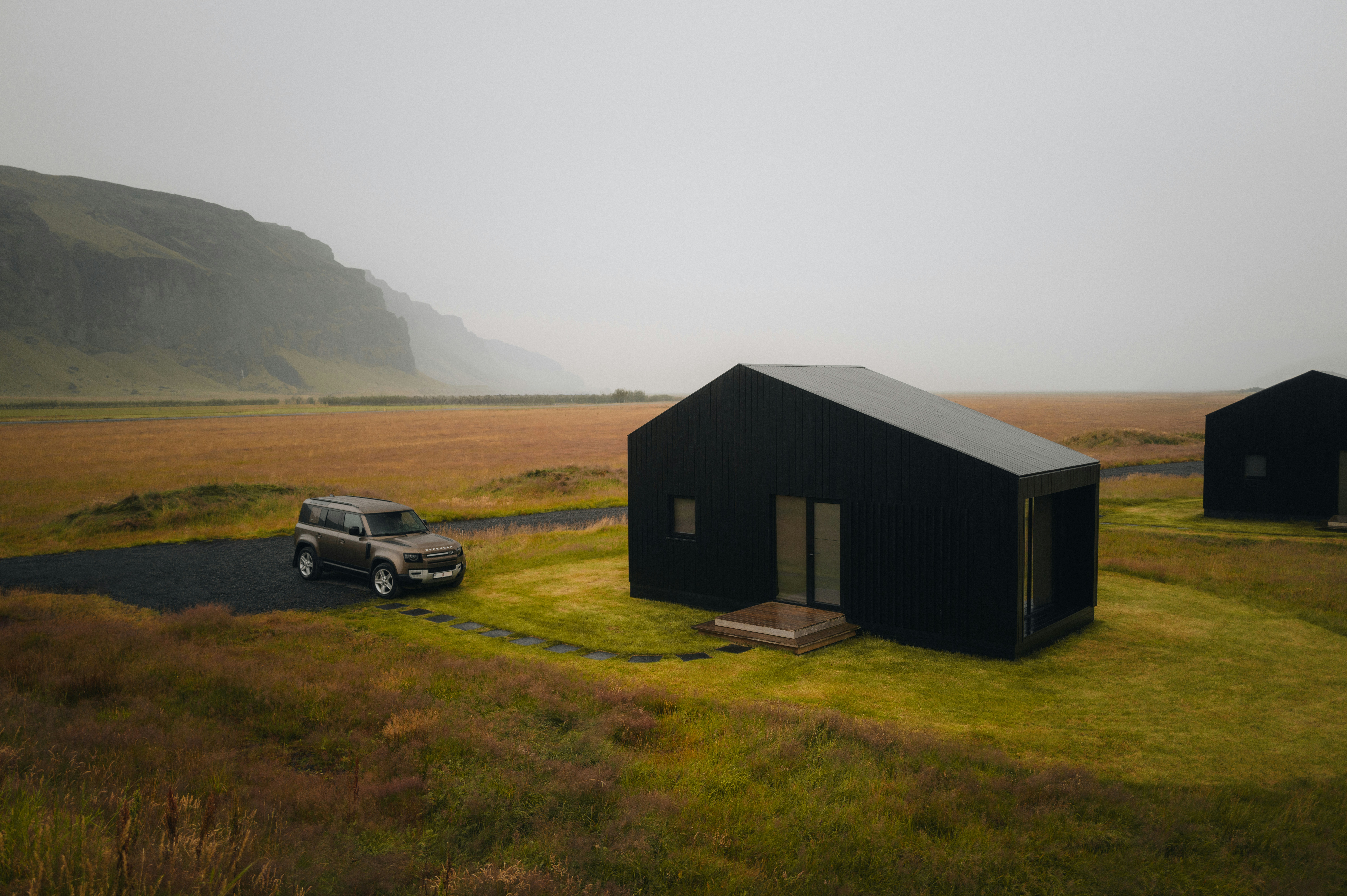 A couple of black buildings sitting on top of a lush green field