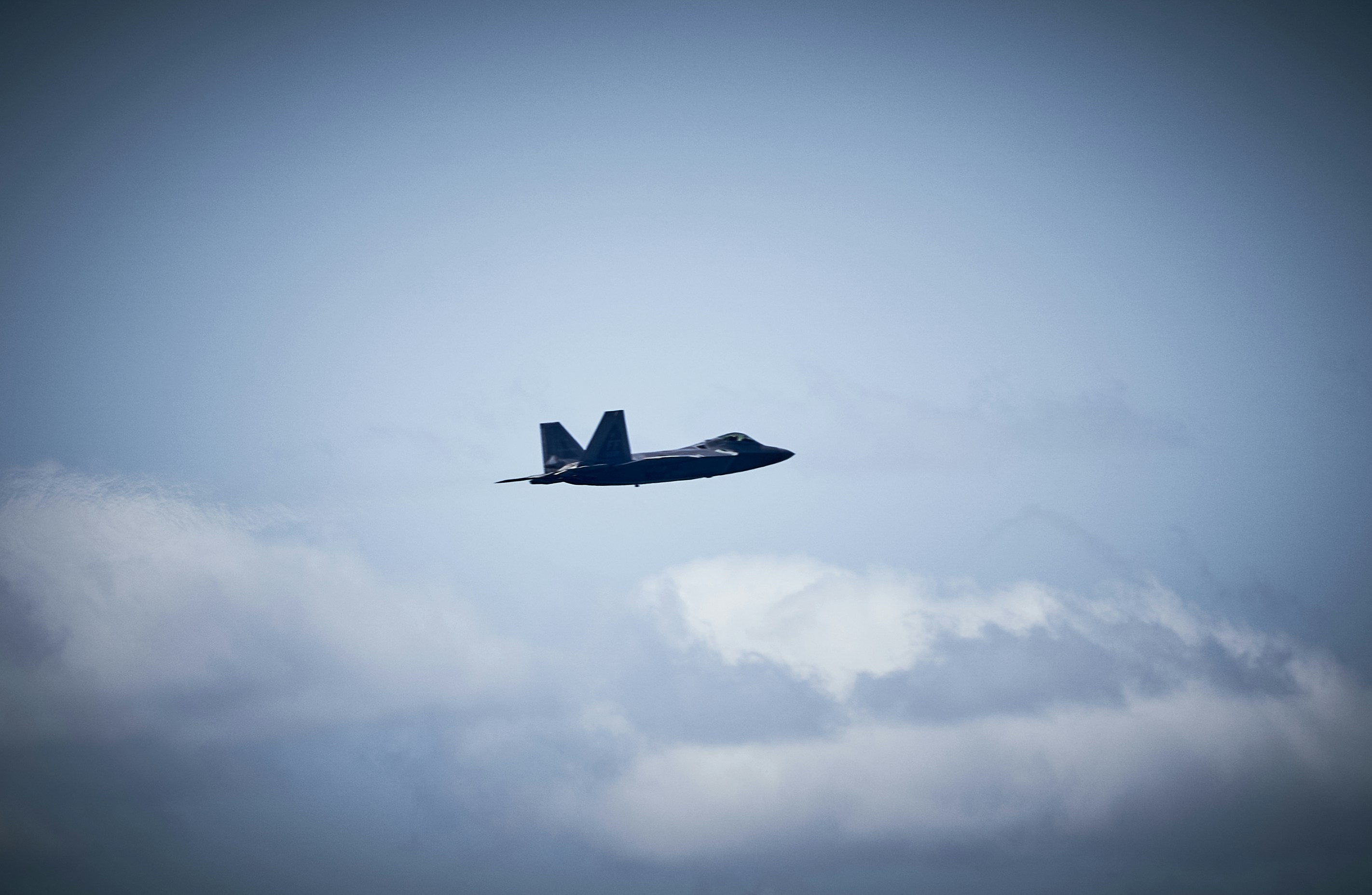 A jet flying through a blue cloudy sky