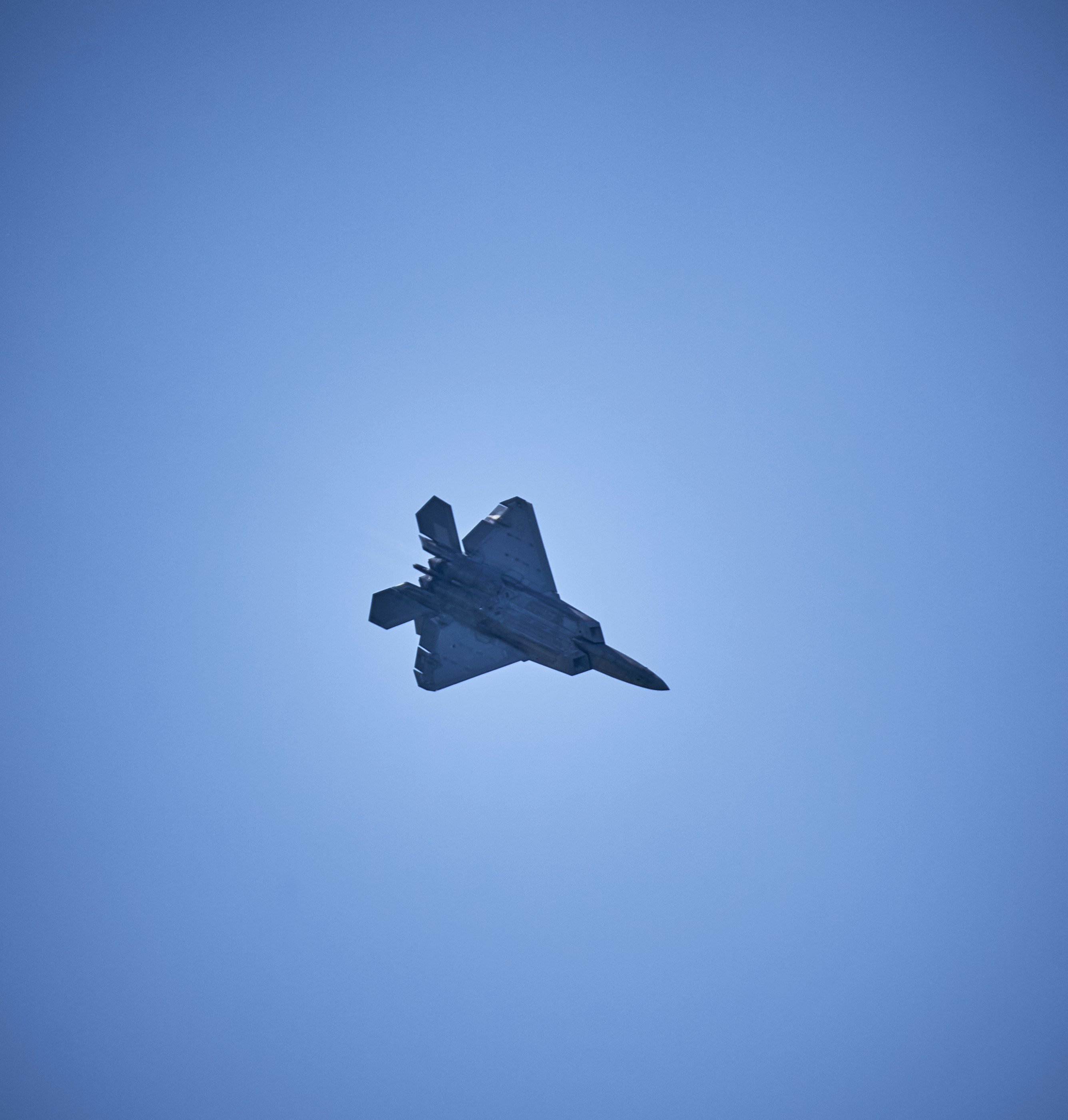 A fighter jet flying through a blue sky