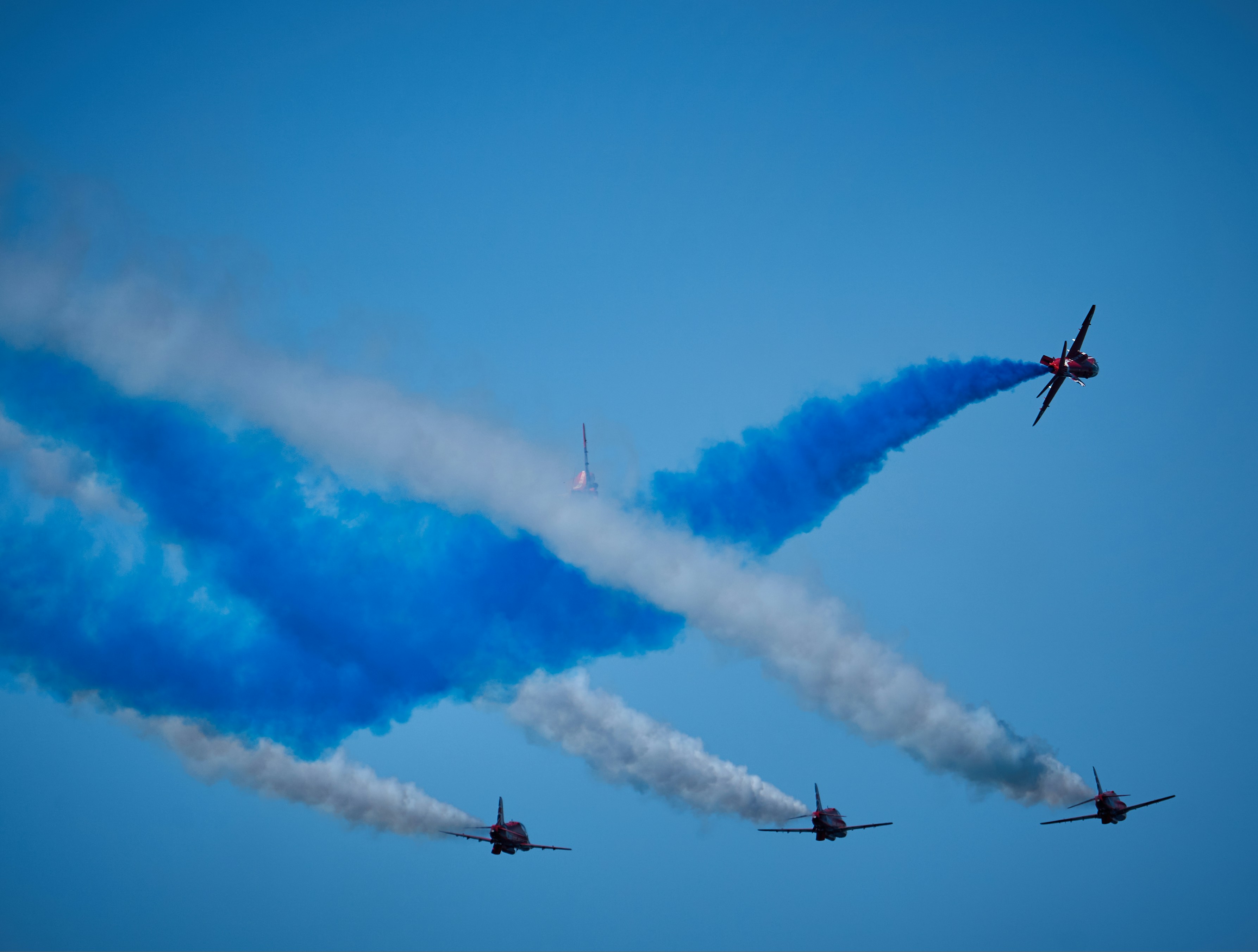 A group of airplanes flying through a blue sky