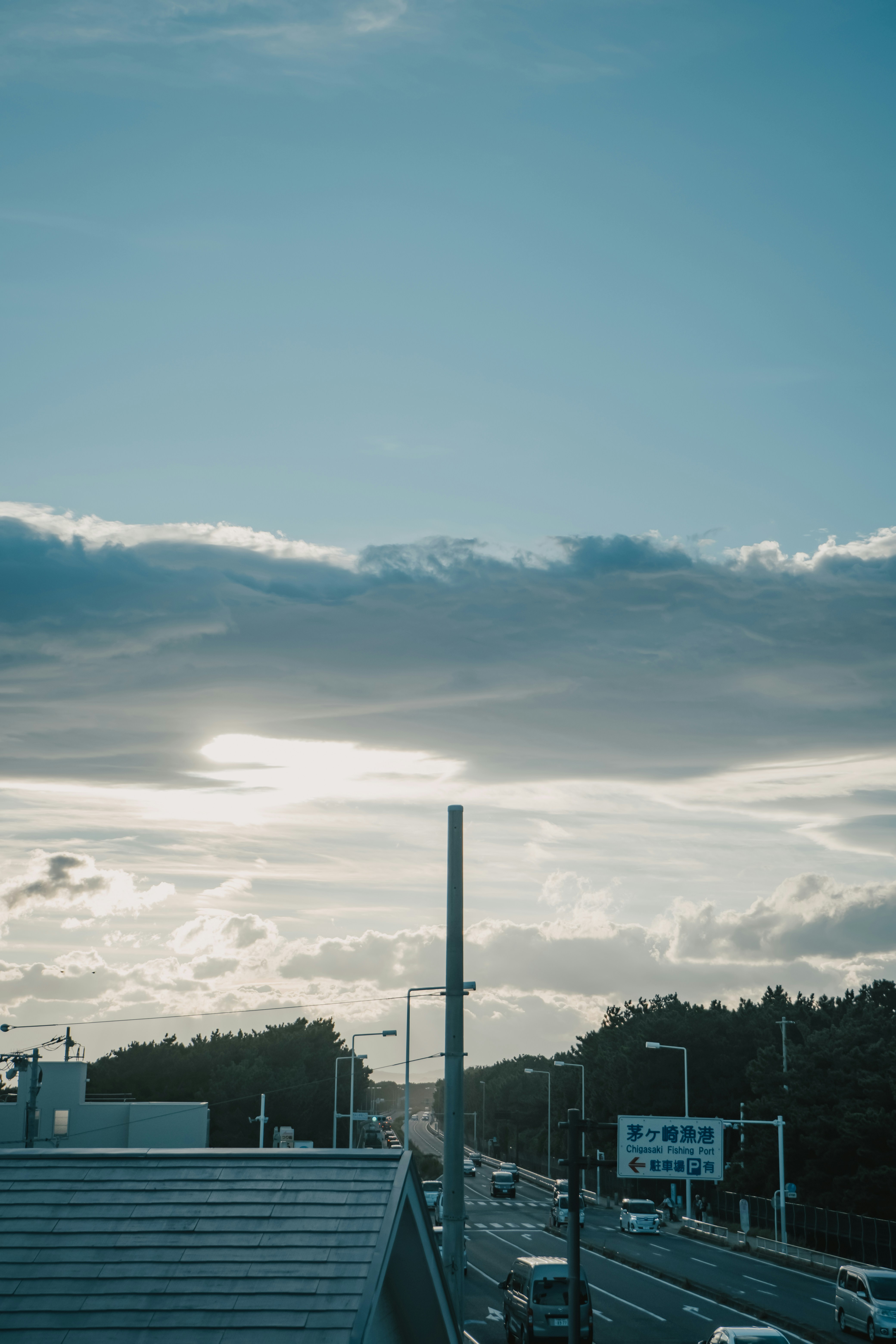 The sun is shining through the clouds over a highway