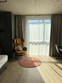 A room with a bed, a chair, a desk and a window