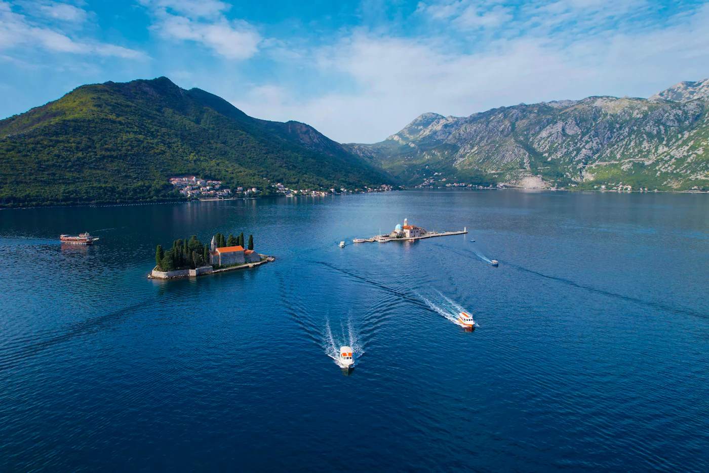 The Bay of Kotor off Perast, with its two island churches and boats crossing the blue water below the mountains