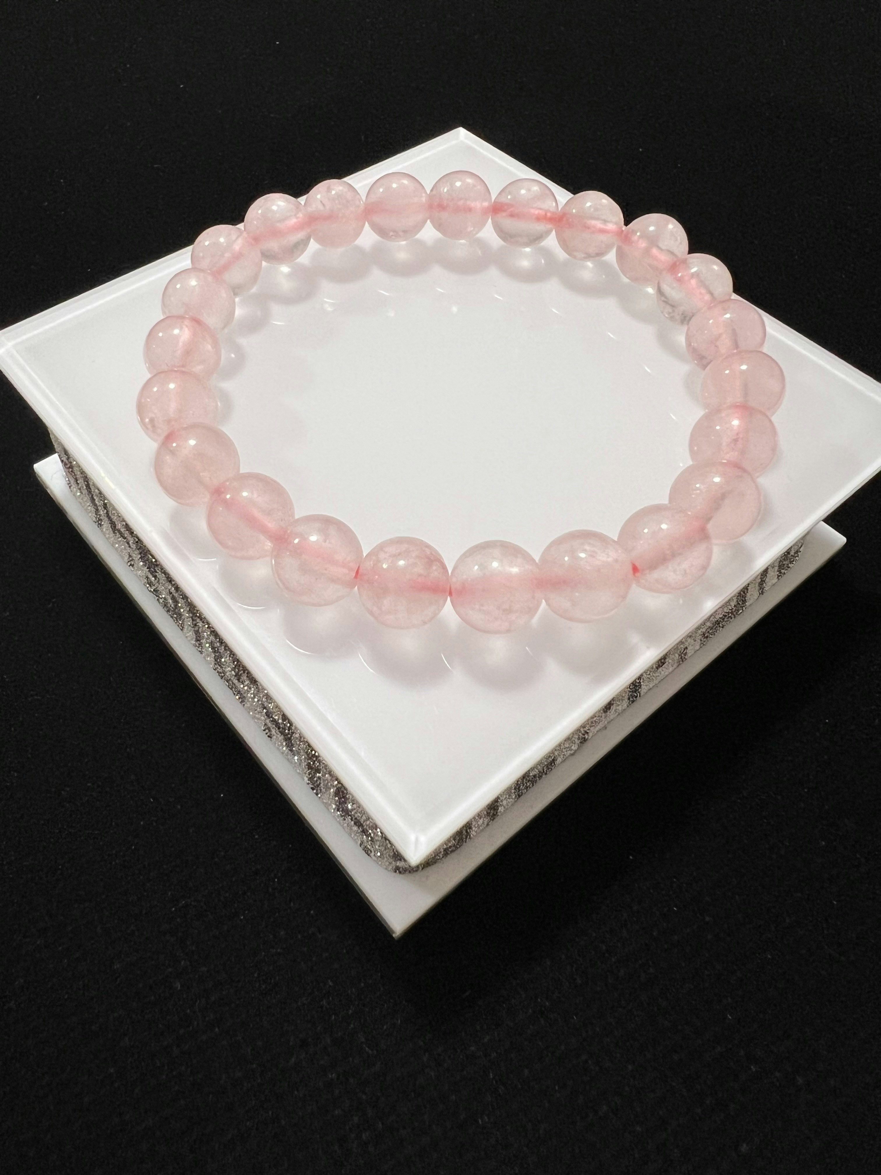 Handmade celestial star and moon bead bracelet in pastel pink and lavender on white surface