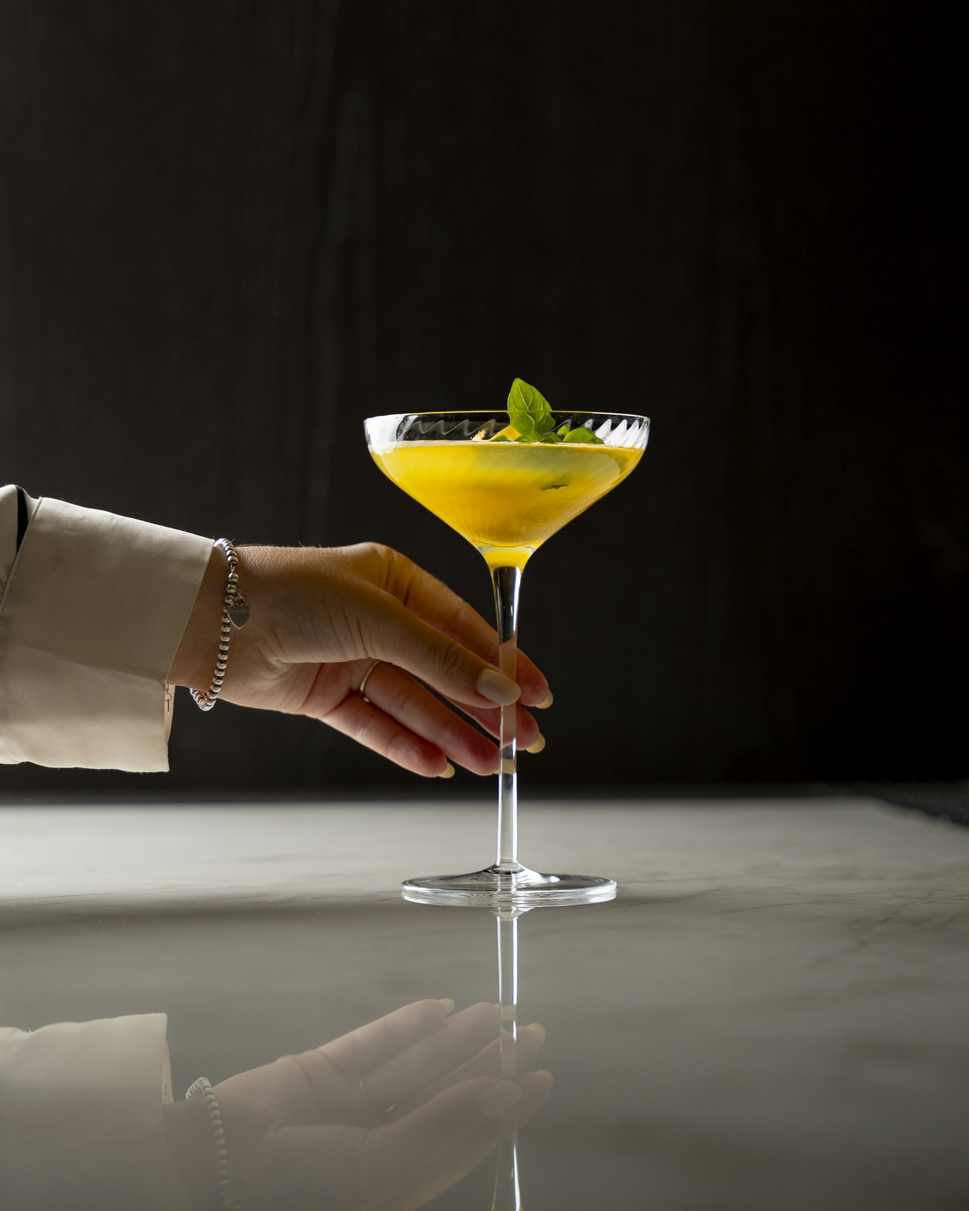 A hand reaching for a drink in a martini glass