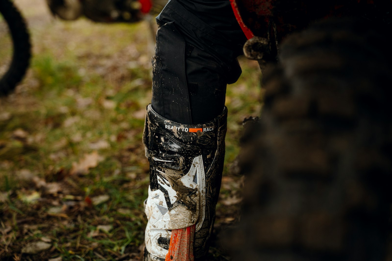 Muddy enduro riding boot next to a dirt bike
