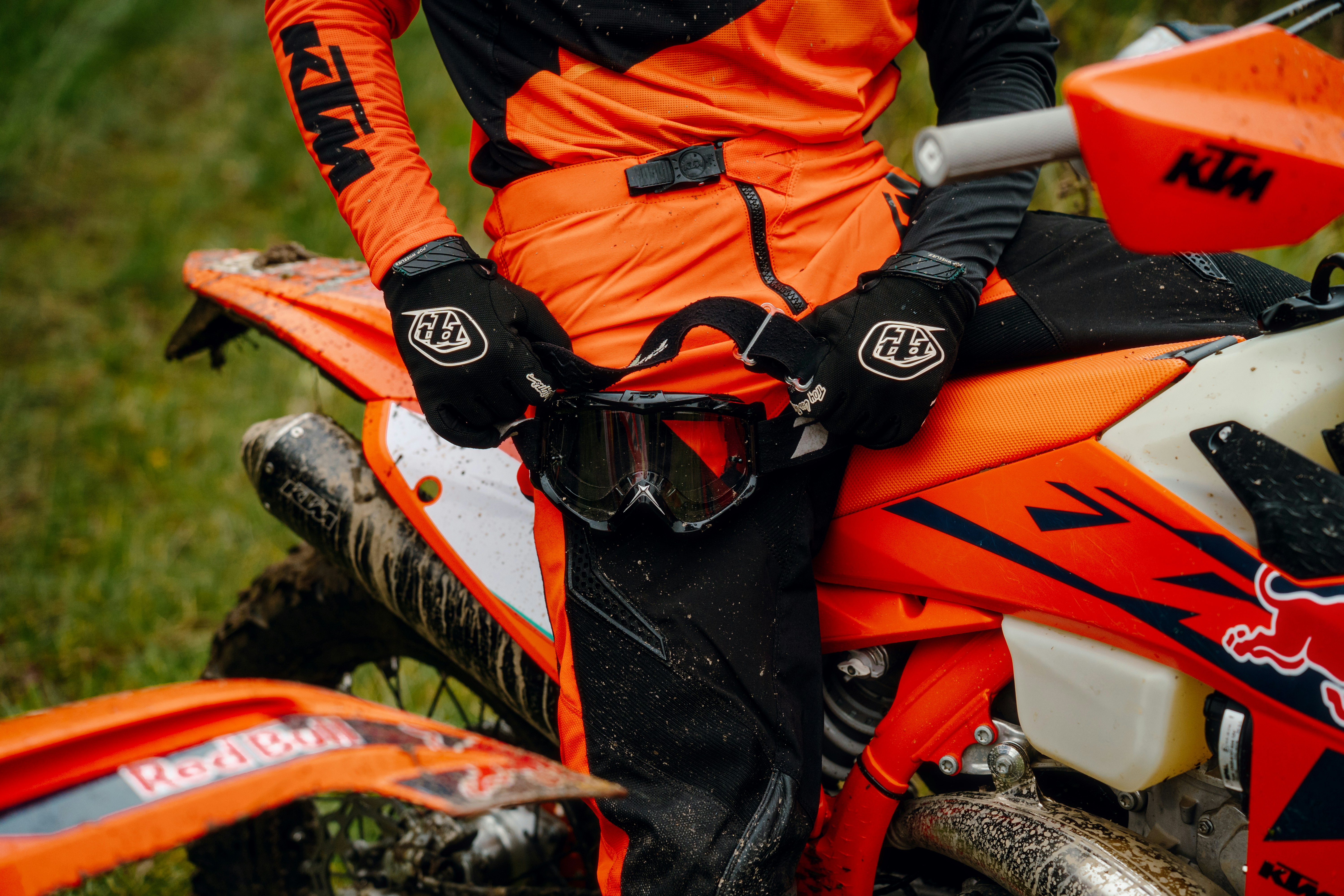 A man in an orange and black outfit sitting on a dirt bike