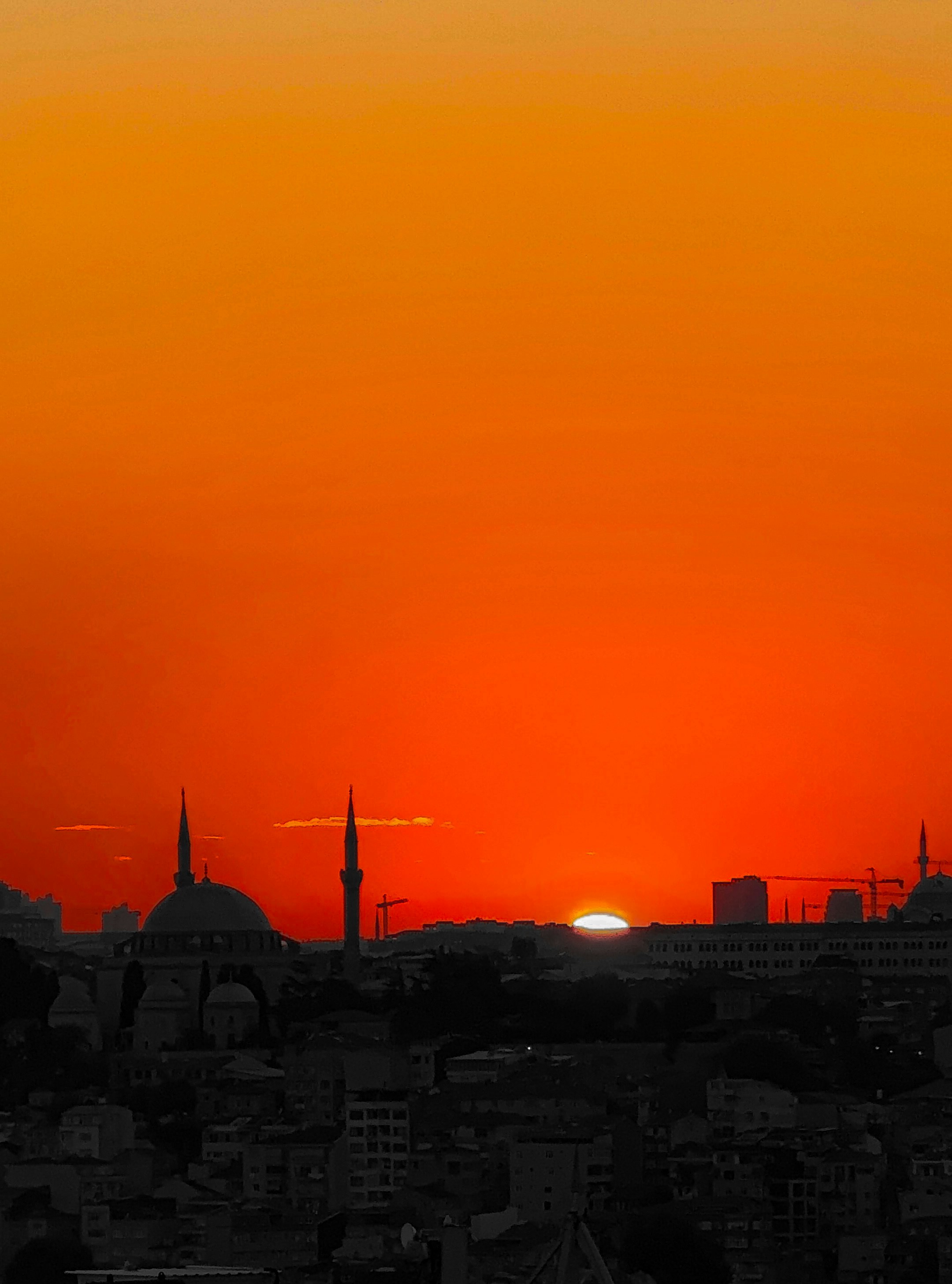 The sun is setting over a city with tall buildings