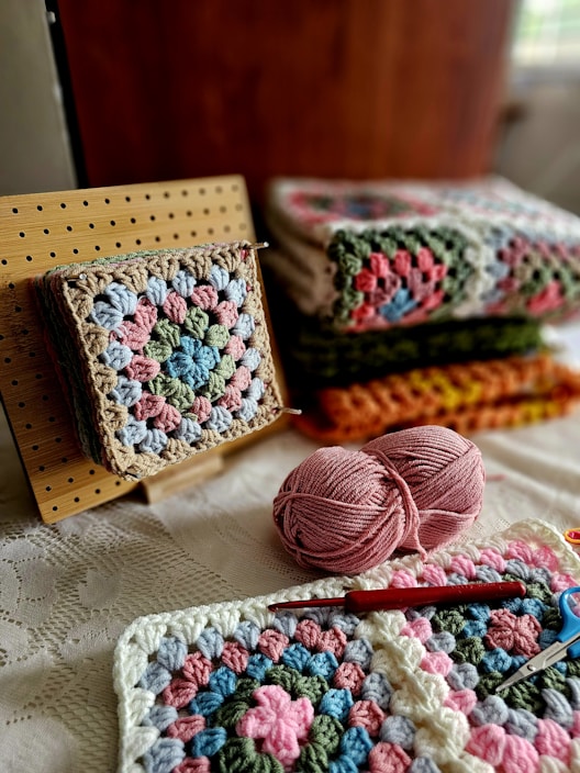 A crocheted blanket and a crochet kit on a bed