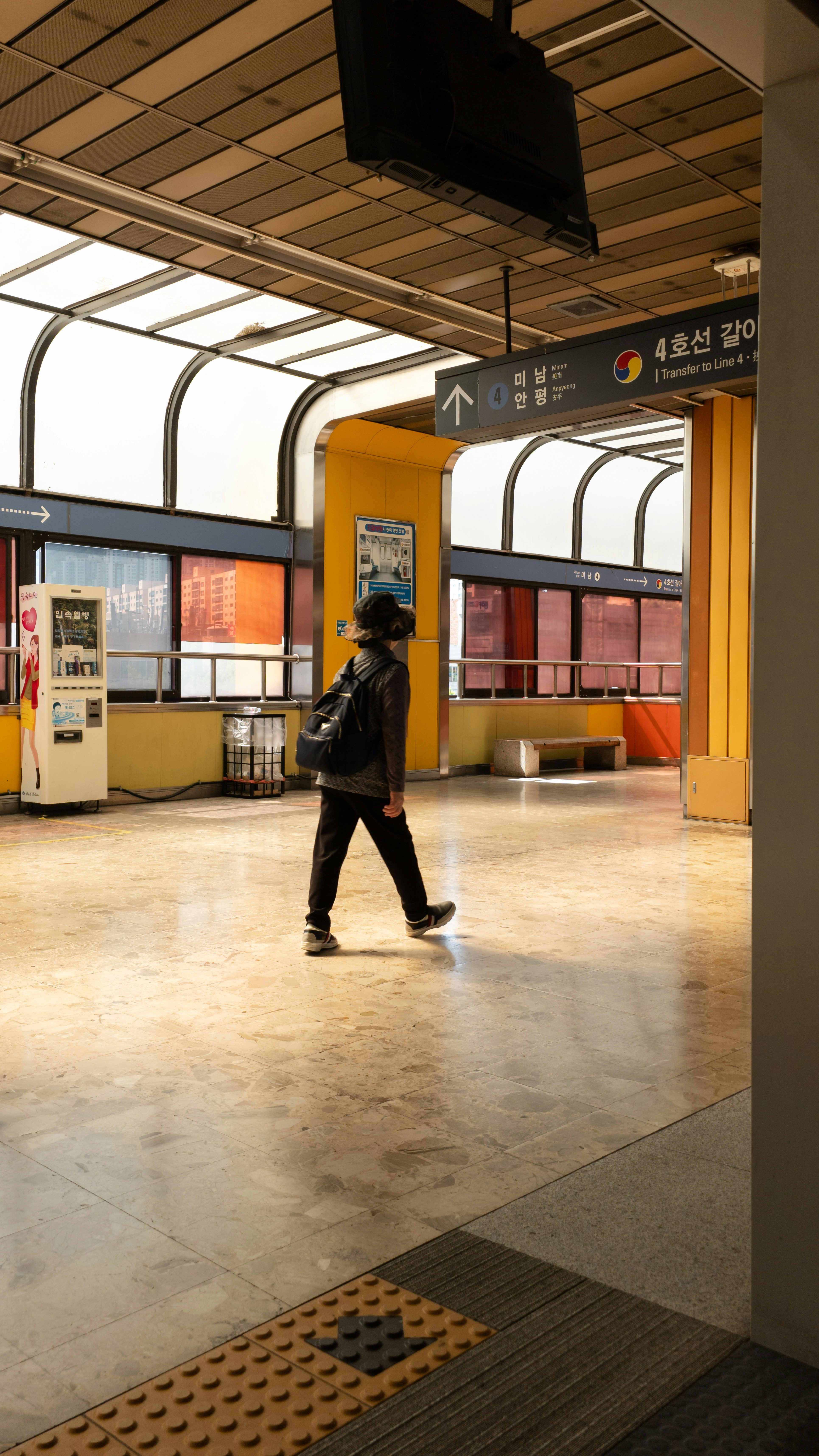 A person walking through a train station next to a train