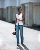 A woman walking down a street holding a purse