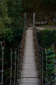 A wooden suspension bridge over a river in the woods