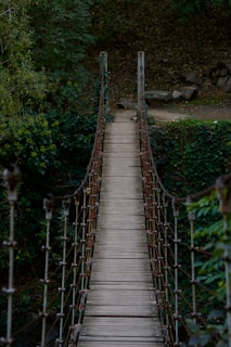 A wooden suspension bridge over a river in the woods