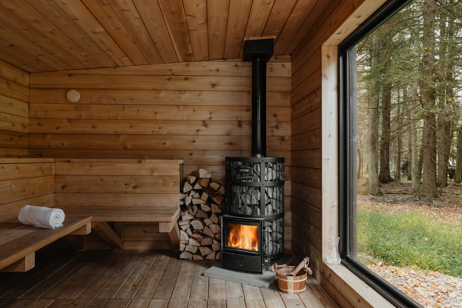 A wood burning stove standing in a plain timber cabin.