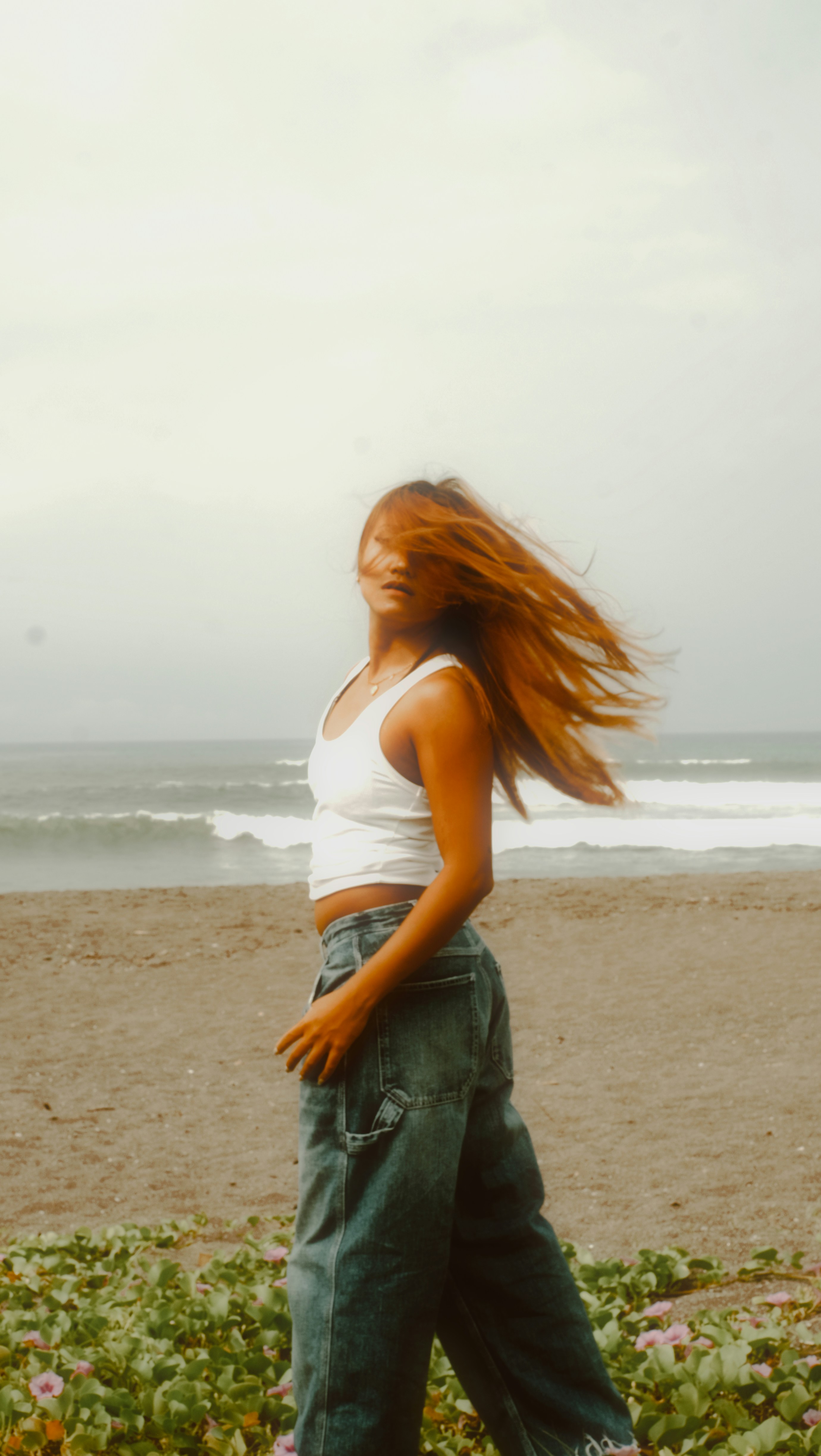 A woman standing on a beach next to the ocean