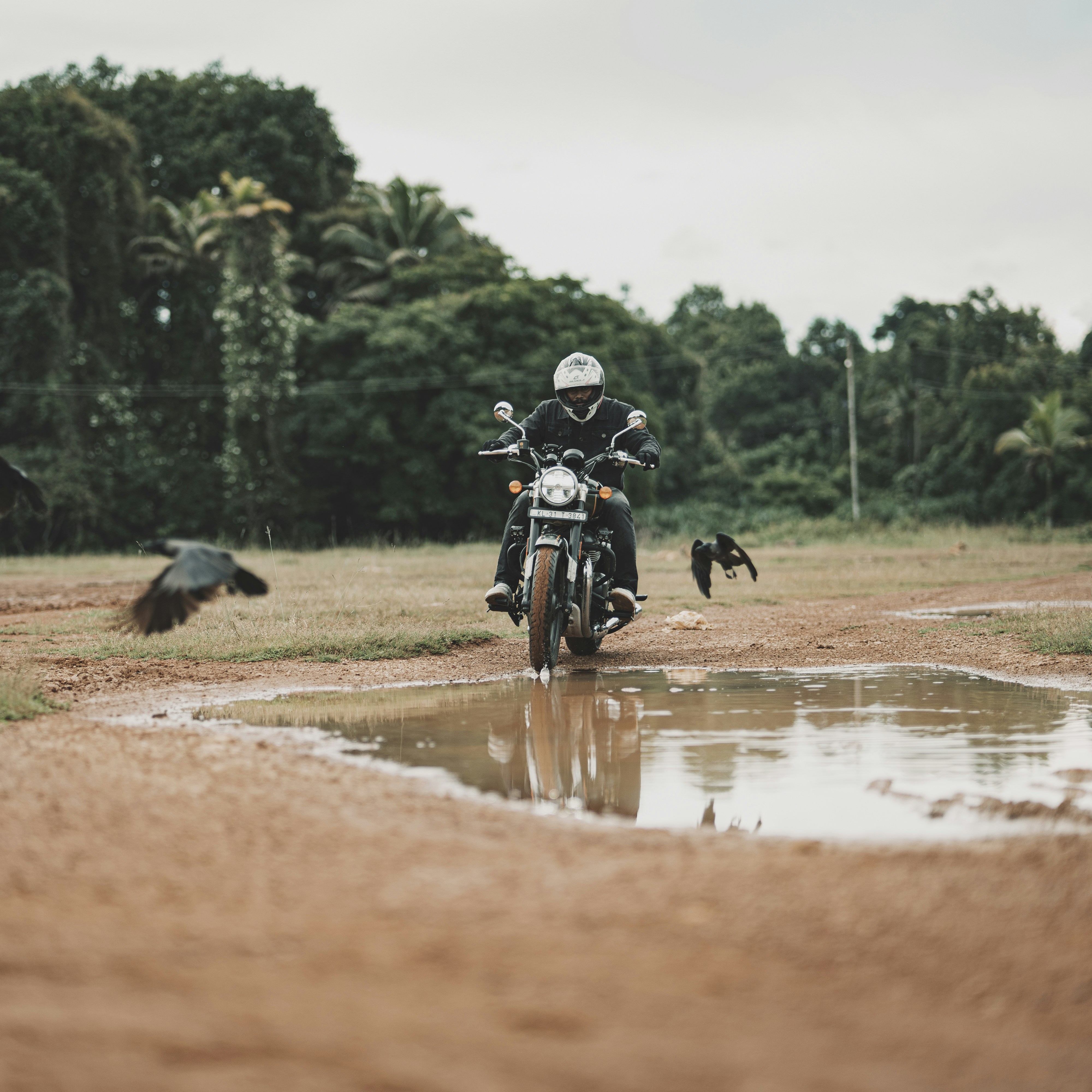 Ein Mann fährt mit einem Motorrad durch eine Wasserpfütze