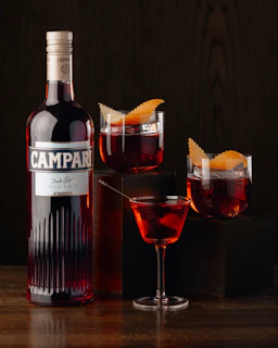A bottle of campari next to a glass of wine