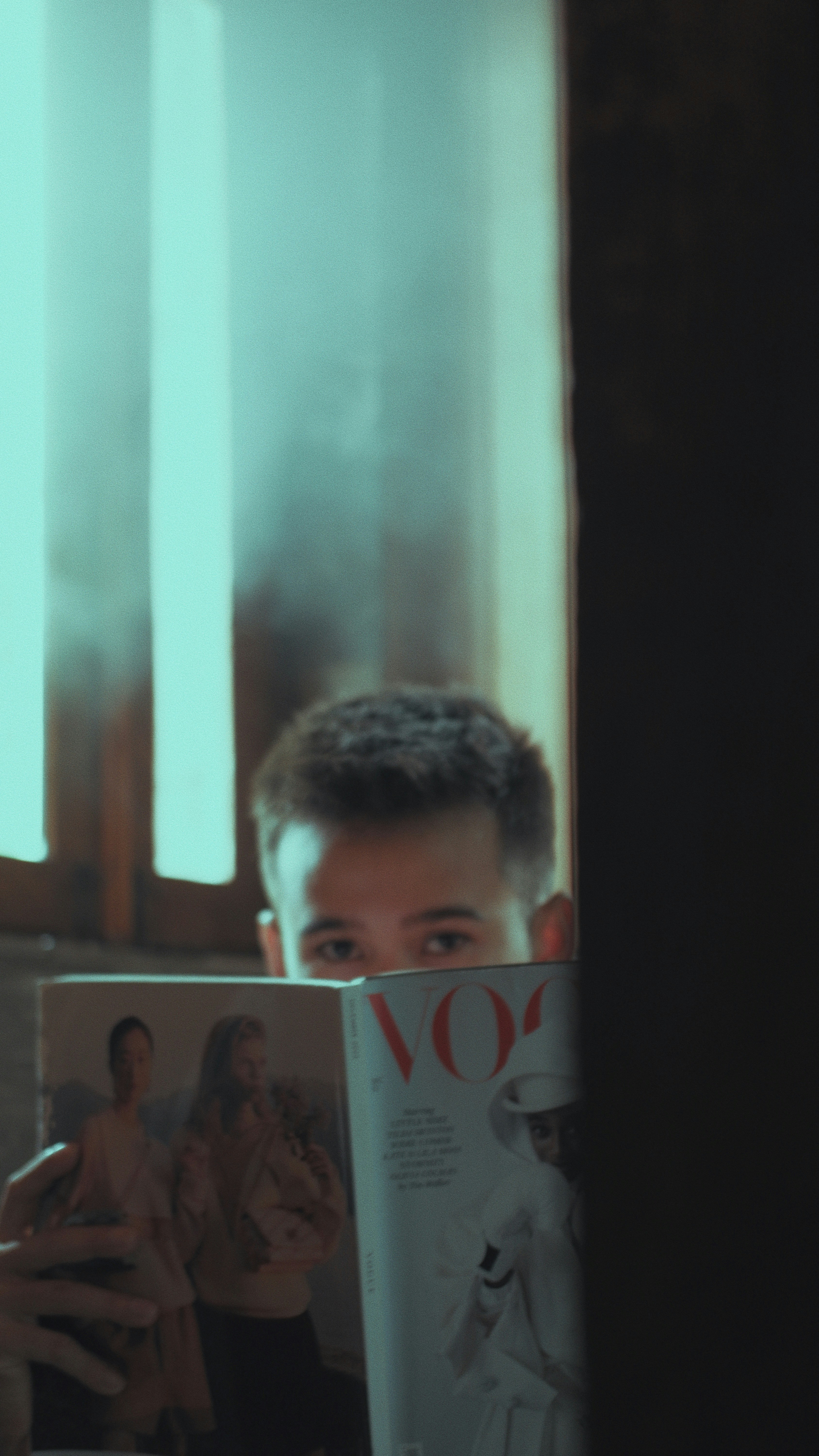 Un hombre leyendo una revista frente a una ventana