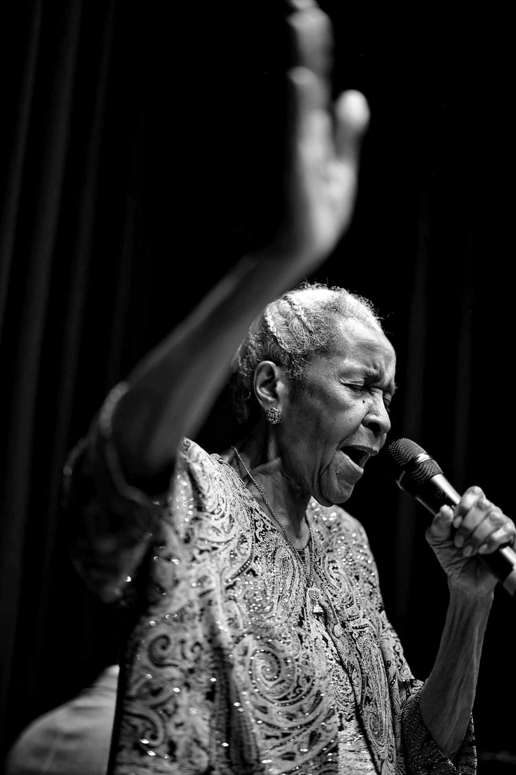 Una foto en blanco y negro de una mujer cantando en un micrófono