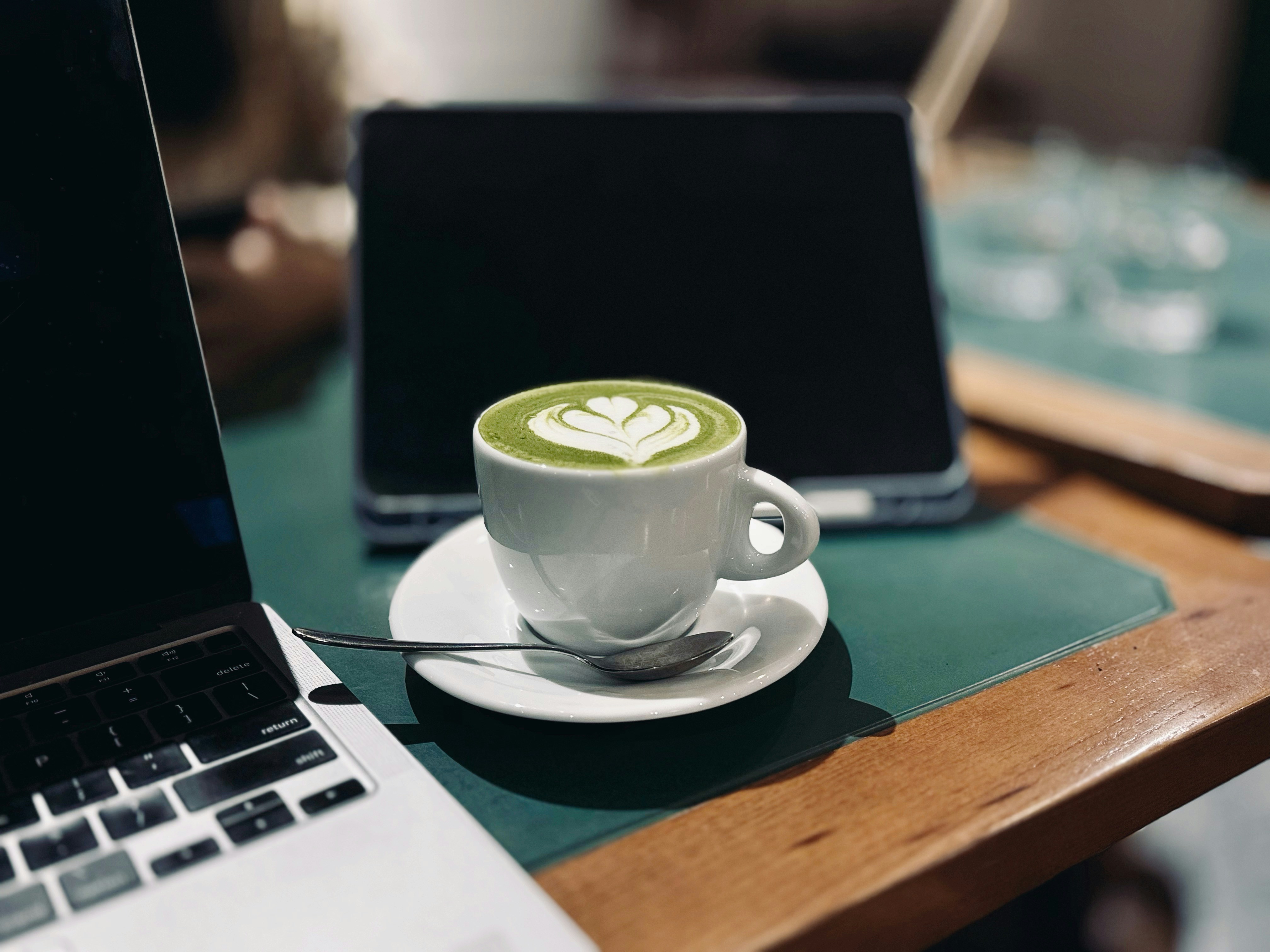Latte with art beside a laptop on a cafe table