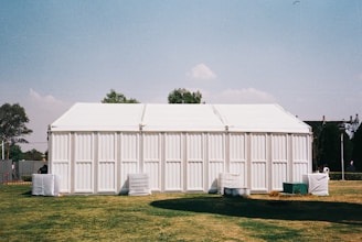 A large white building sitting on top of a lush green field