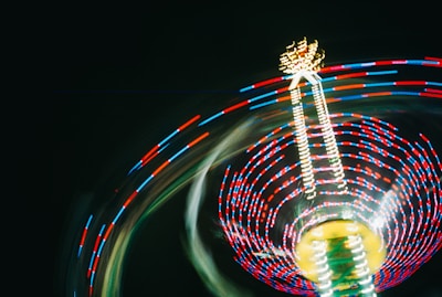 A ferris wheel spinning at night with a blurry background