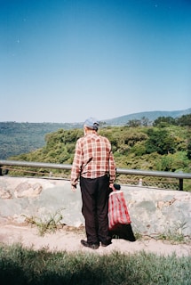 A man standing on a hill with two bags of luggage