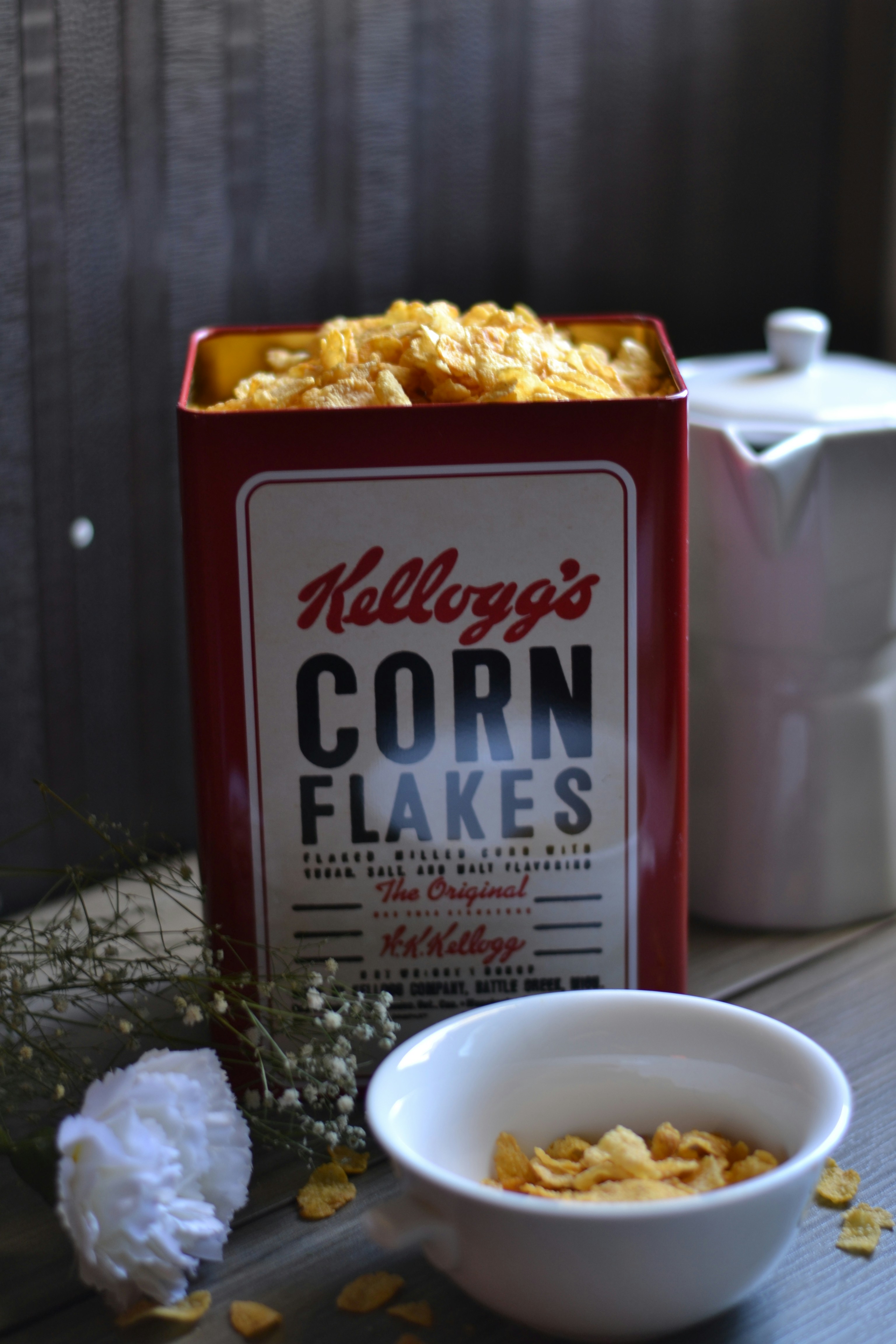 A box of corn flakes next to a bowl of cereal