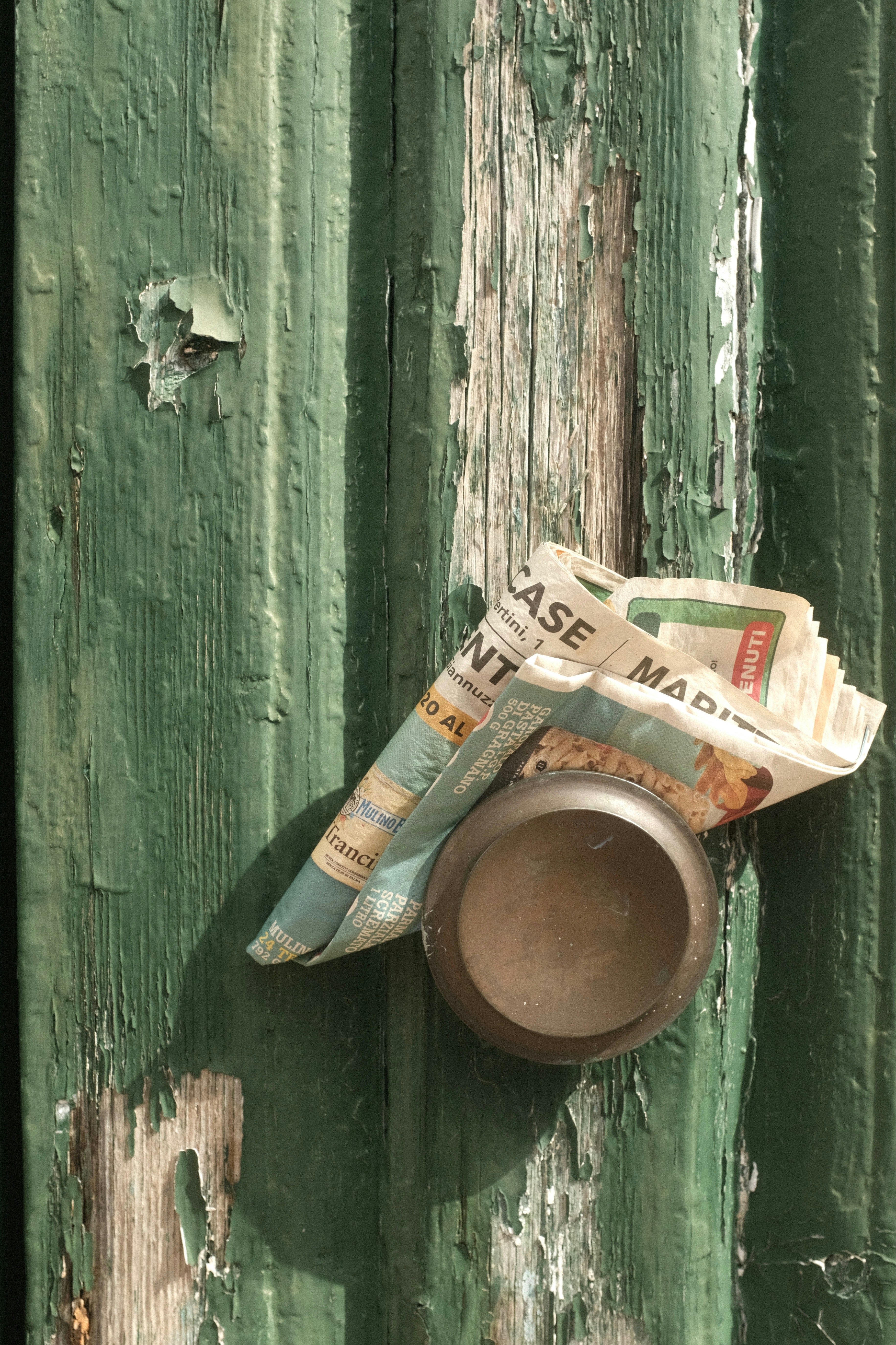 A piece of newspaper is hanging on a green door