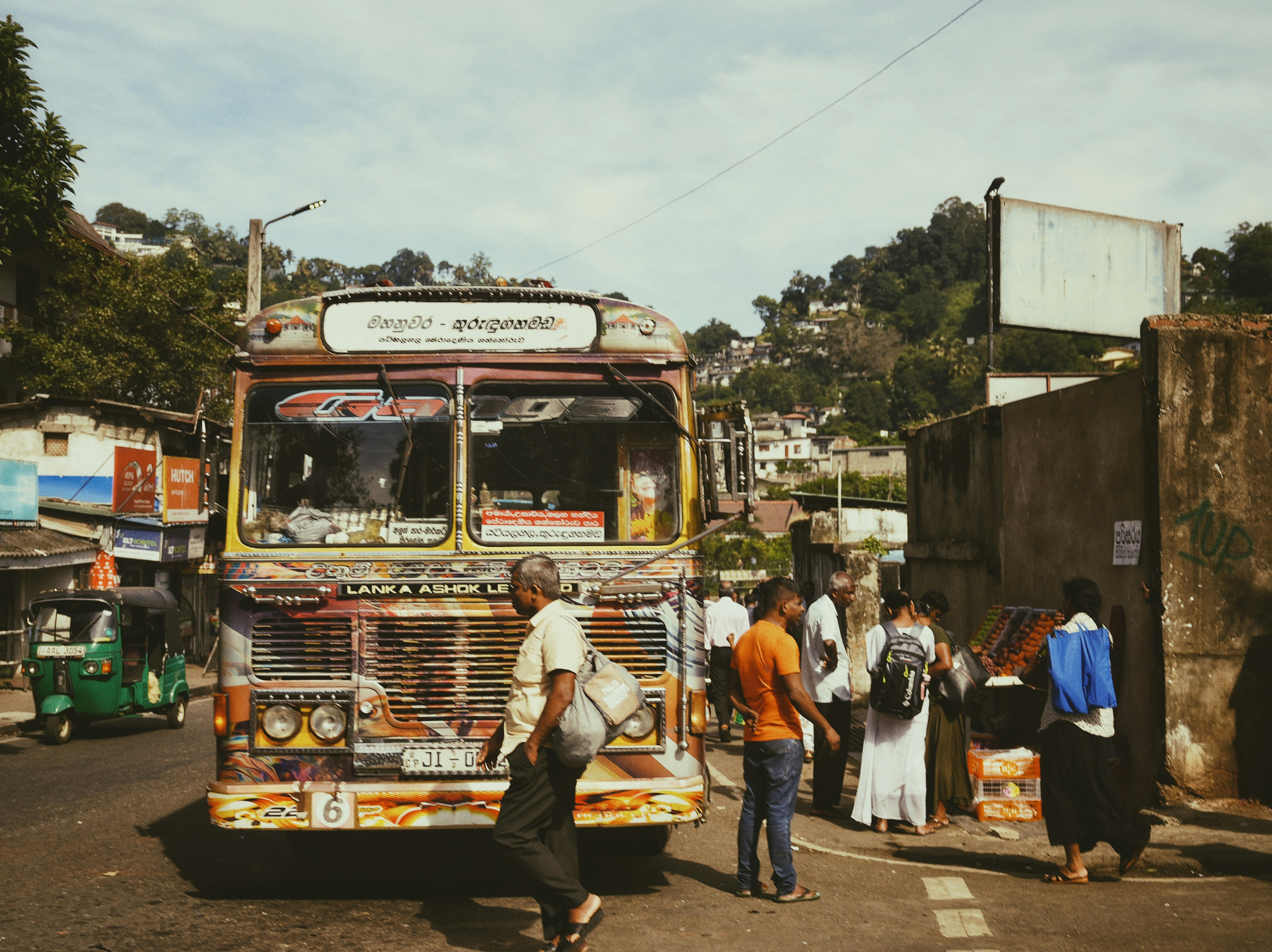 A group of people walking across a street next to a bus