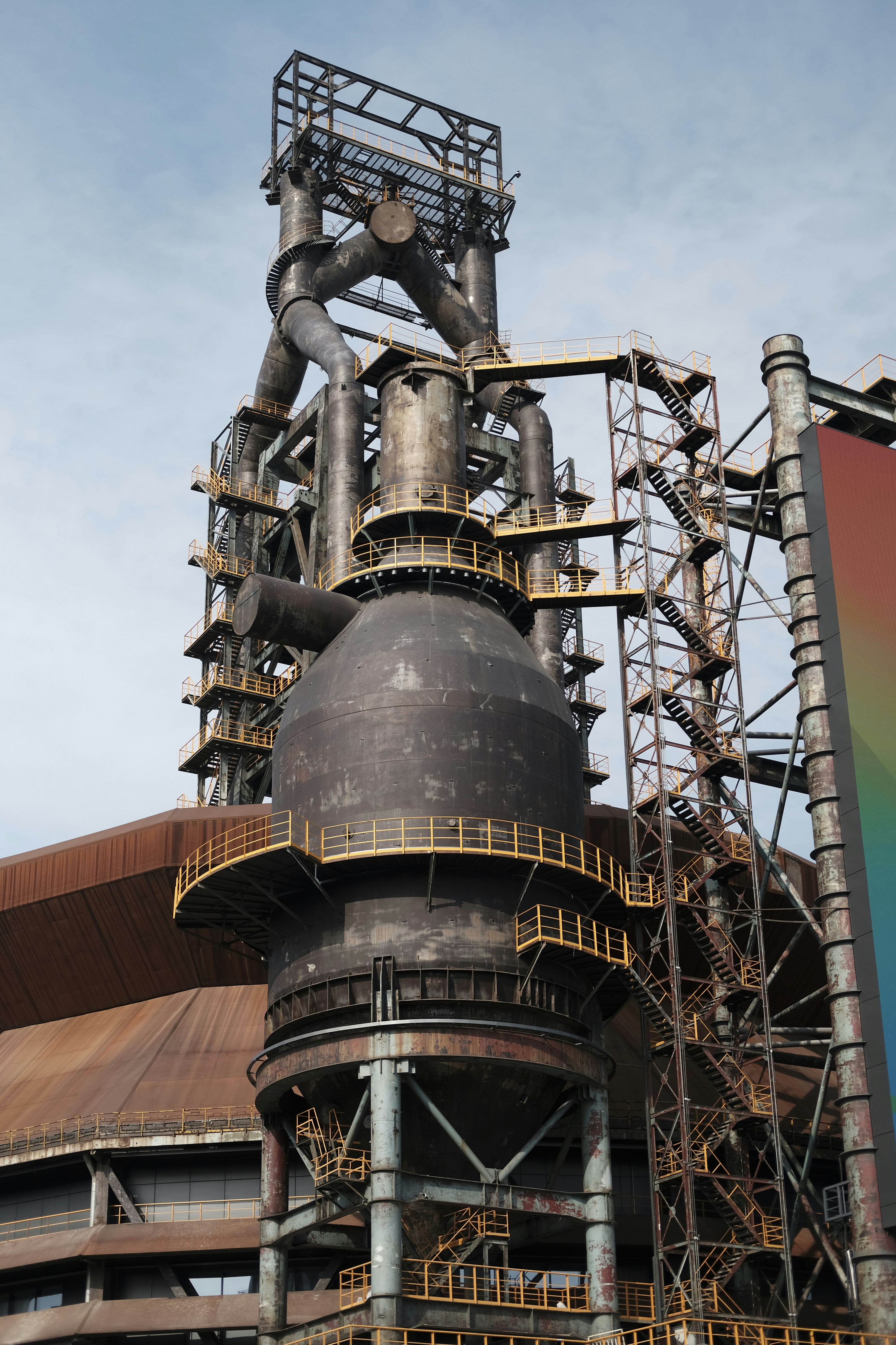 A large metal structure with a rainbow flag in front of it
