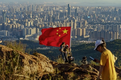 A man standing on top of a mountain next to a flag