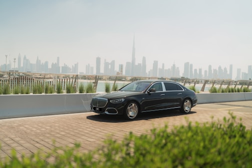 A black car driving down a road next to a city
