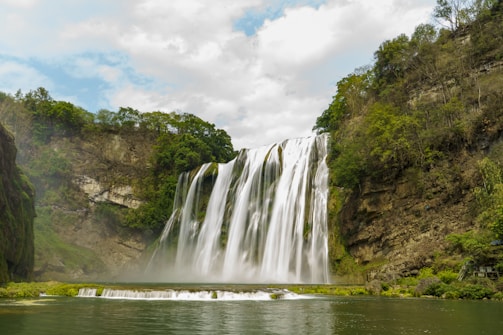 A large waterfall with a body of water in front of it