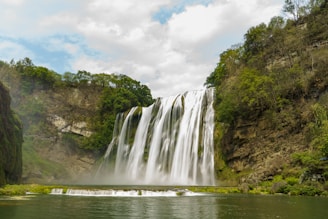 A large waterfall with a body of water in front of it