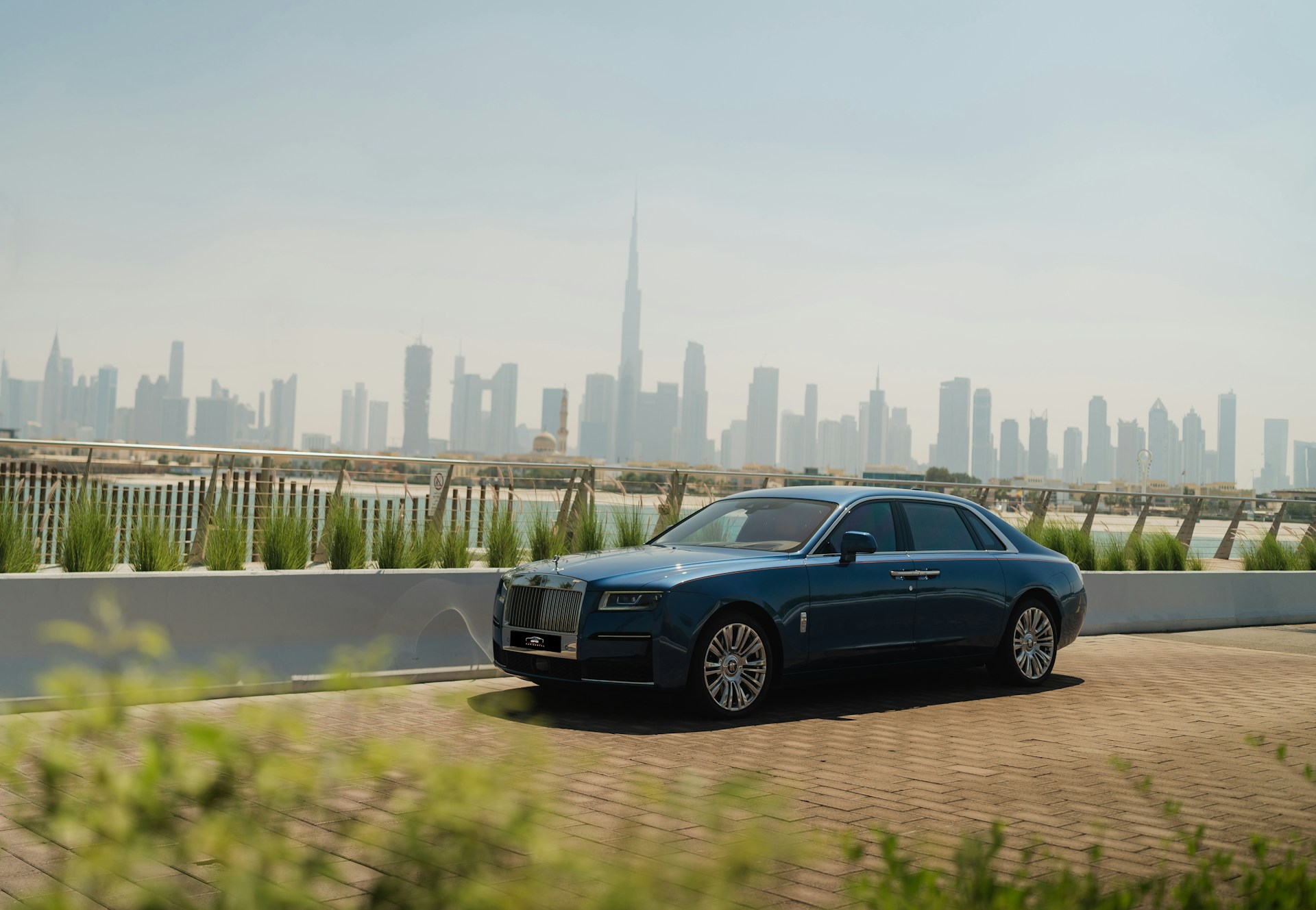 A blue car driving down a road in front of a city