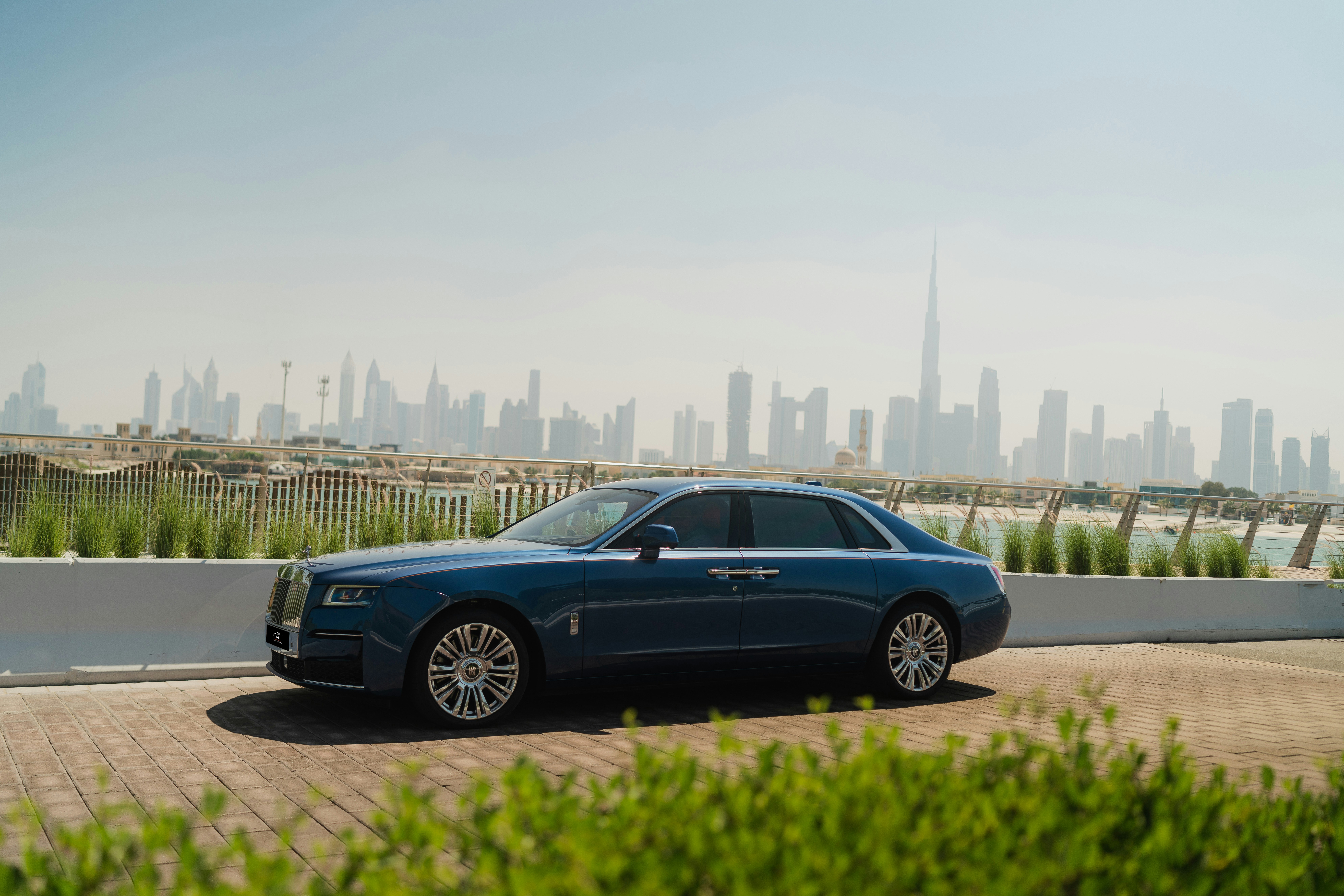 A blue rolls royce parked in front of a city
