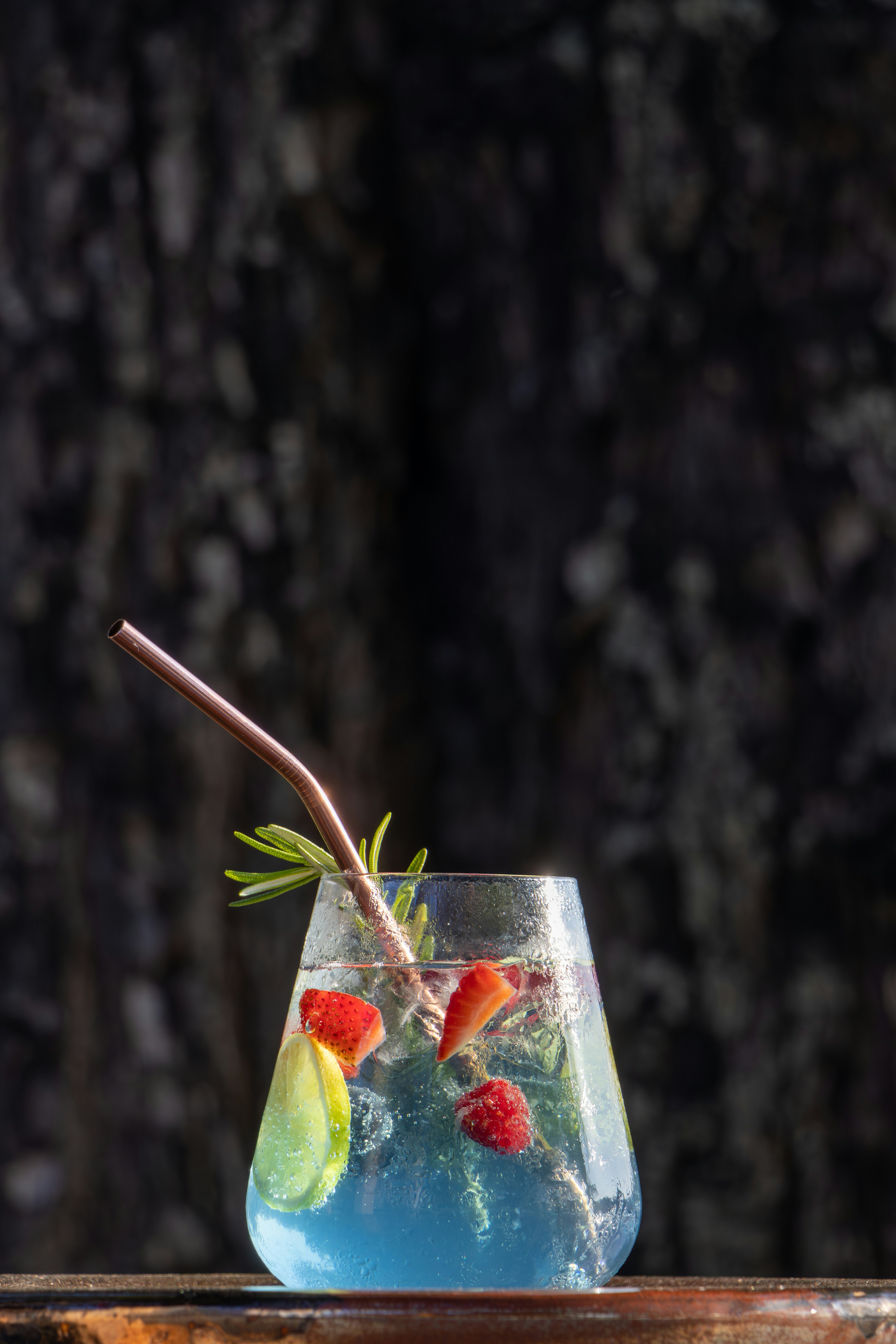A glass filled with blue liquid and strawberries